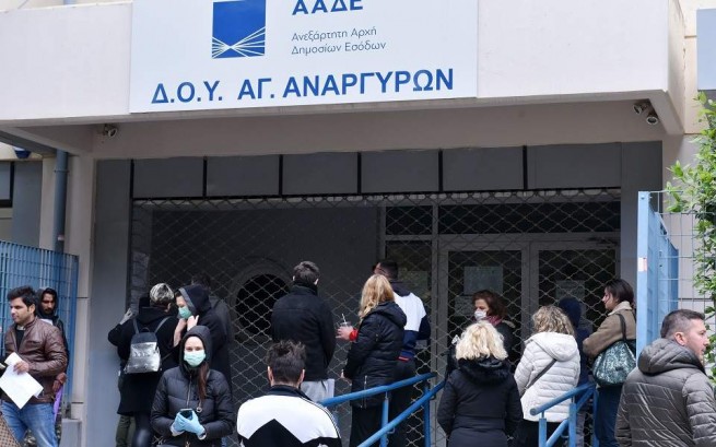 Представители общественности возле налоговой службы в Афинах, которая закрыта ставнями